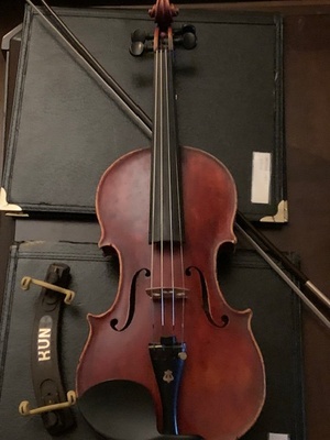 A Violin with a reddish hue atop a bow