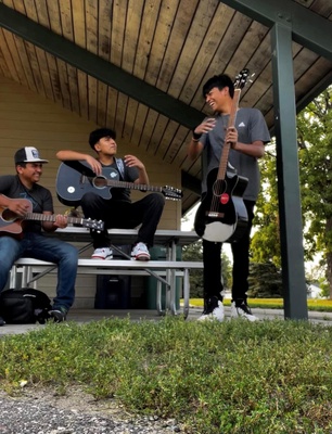 Friends playing guitar at the park.