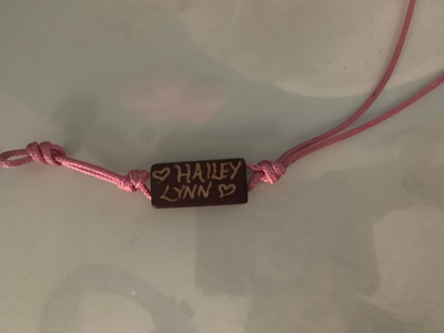 A bracelet with pink string and a name.