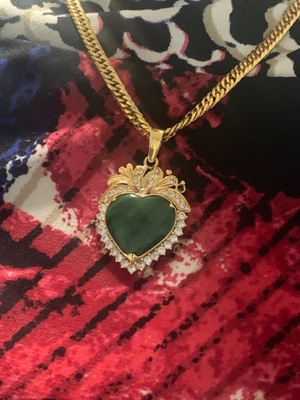 a gold chain holds a heart-shaped jade