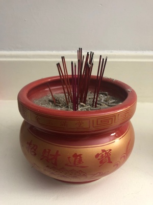 The red/brownish pot with incense sticks