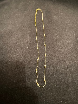 A gold necklace with white beaded pearls