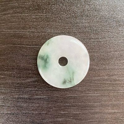 A circular white jadeite pendant.