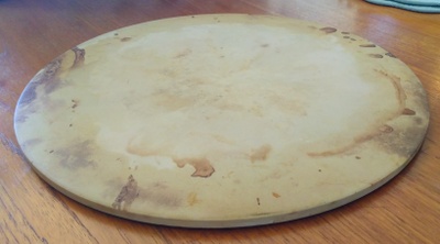 Photo of round, pizza stone on a table.