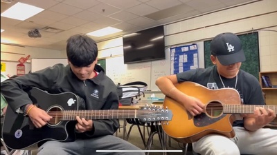 Two students playing guitar