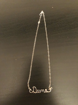 This is necklace made out of silver, holding my name with a purple gem next to 