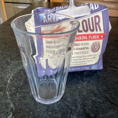 A clear drinking glass and bag of flour.